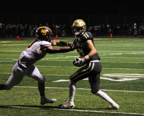 Grady Falkenstein (#11) enters a clash with a Walsh player during the Mum Day game, perfectly representing Hoban and Walsh’s rivalry and showcasing the determination and pride that both teams brought to the field this year. PHOTO COURTESY OF ELAINA KARAFILIS